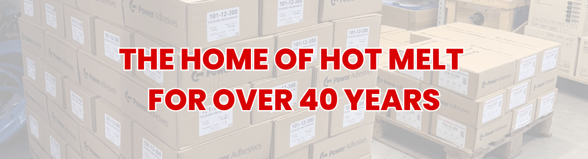 Pallets of Tecbond glue stick boxes by power adhesives in the Gluesticks UK warehouse, as a faded background. Text overlay stating "The home of hot melt for over 40 years".